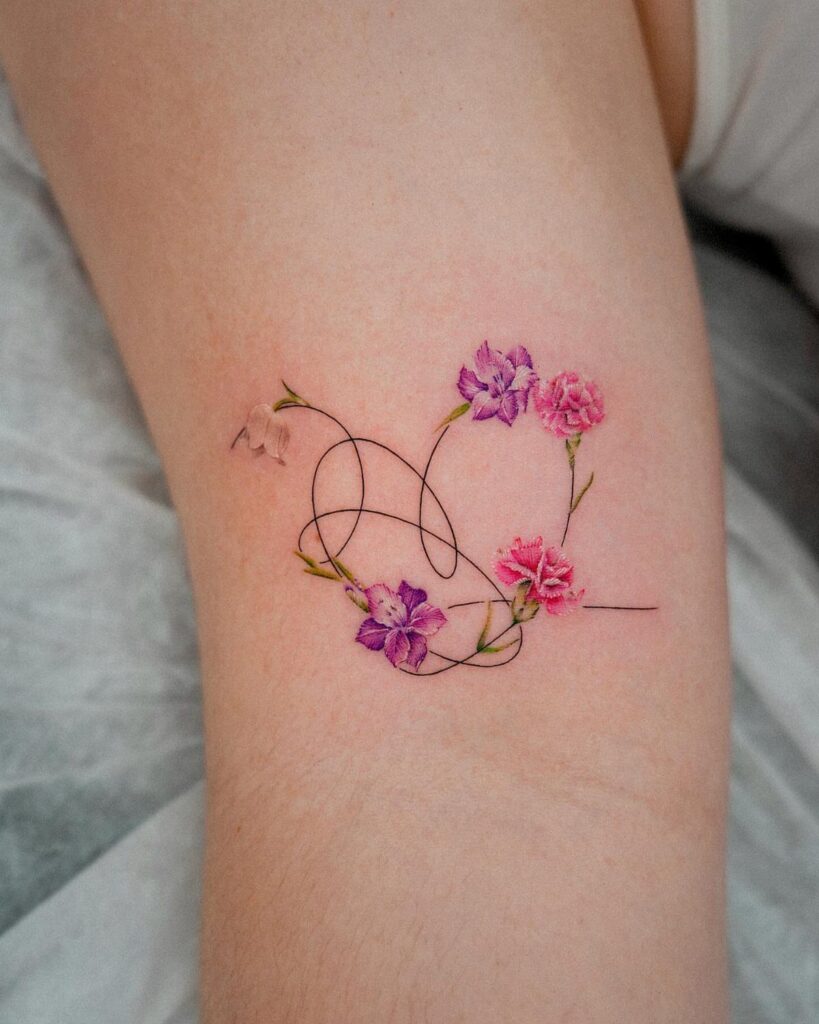 Heart-shaped tattoo with pink and purple flowers on a person's skin.