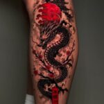 Asian dragon tattoo on a leg with red sun and pagoda silhouette