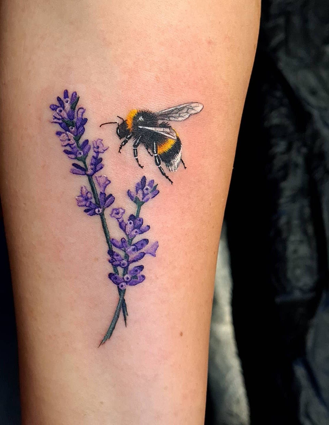 Bumble bee and purple lavender tattoo on a person's arm.