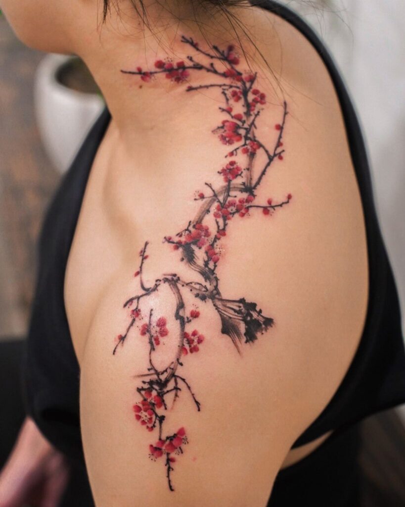 Cherry blossom branch tattoo with red flowers on a person's shoulder and neck