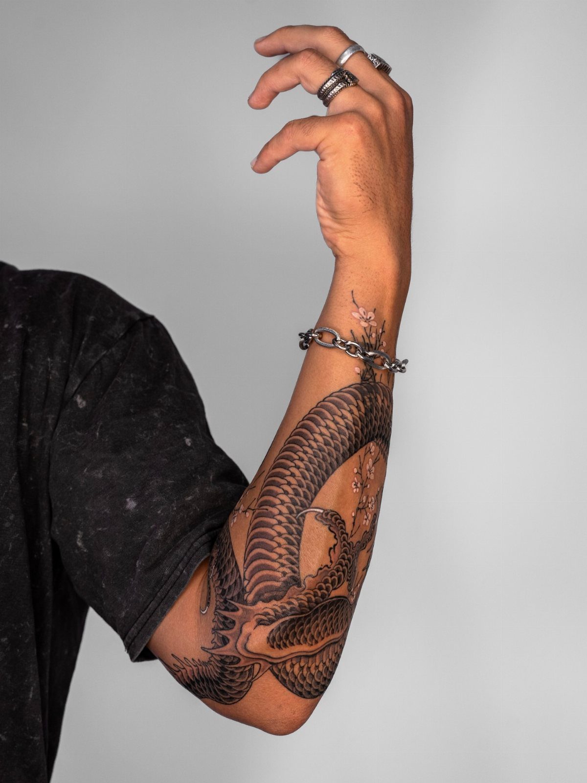 Detailed black ink dragon tattoo wrapping around a person's forearm and wrist.