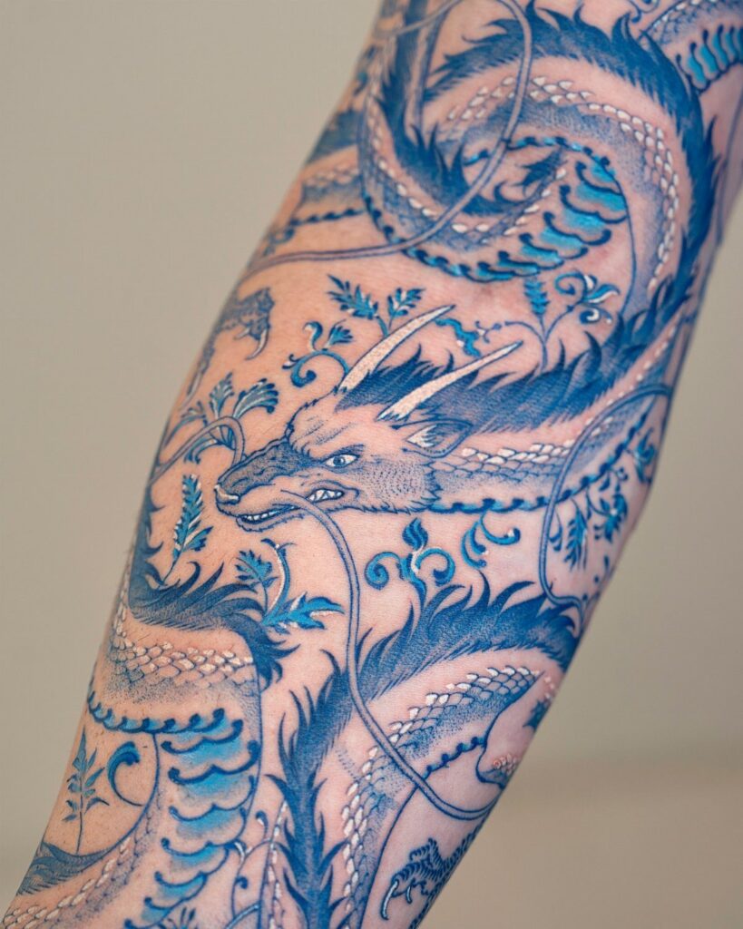 Blue dragon tattoo with intricate scales and waves on a person's arm