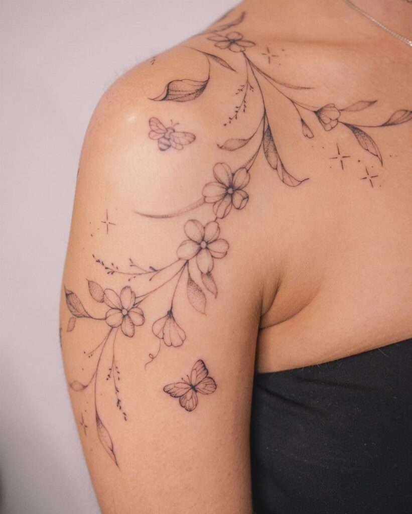 Floral tattoo with butterflies and stars on a person's shoulder and collarbone