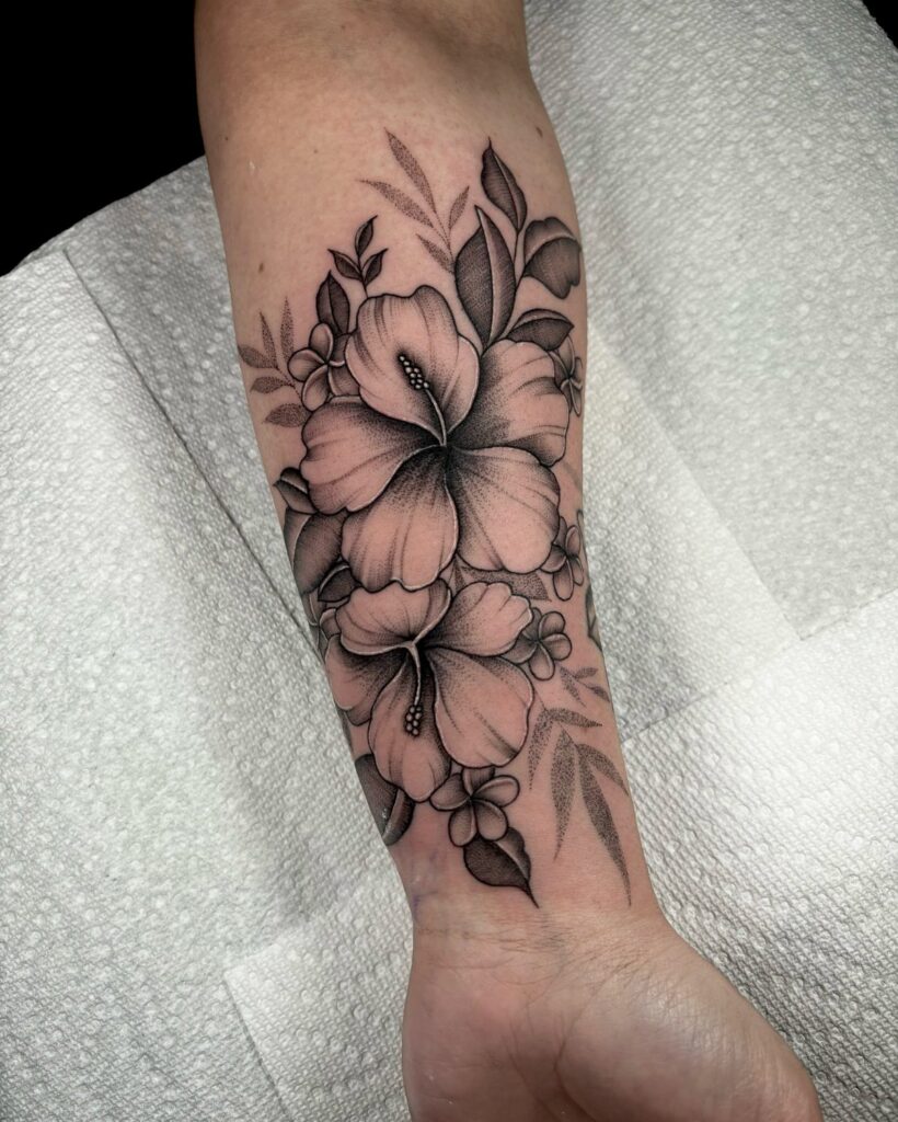 Hibiscus flower tattoo in black and grey ink on a person's forearm