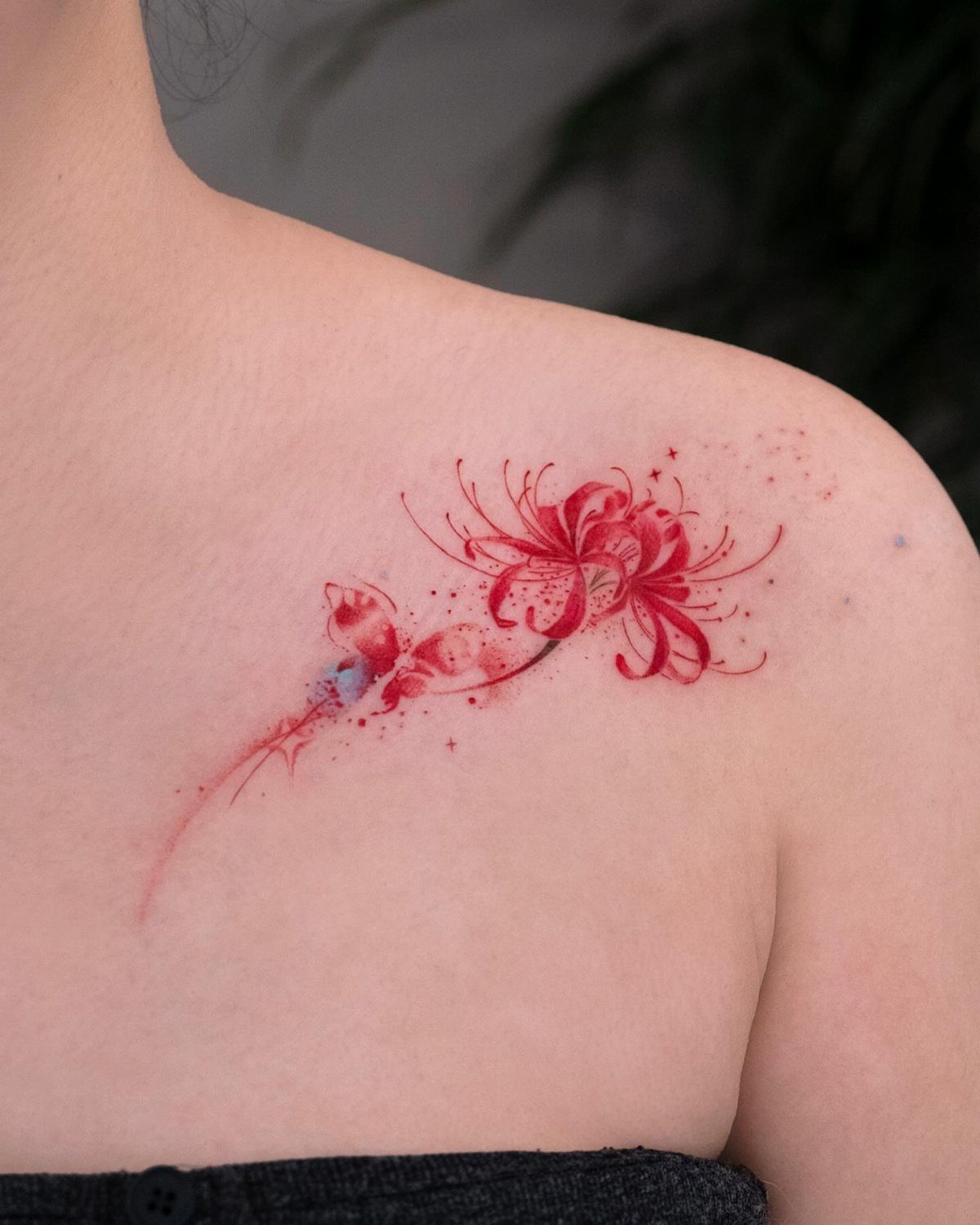 Red spider lily and butterfly tattoo on a person's shoulder and upper back