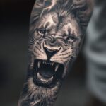 Roaring lion head tattoo with lightning bolts on a person's forearm
