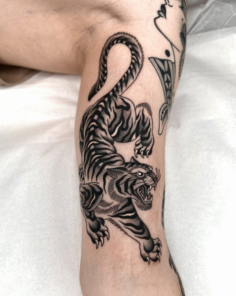 Traditional black and grey tiger tattoo on a person's lower leg