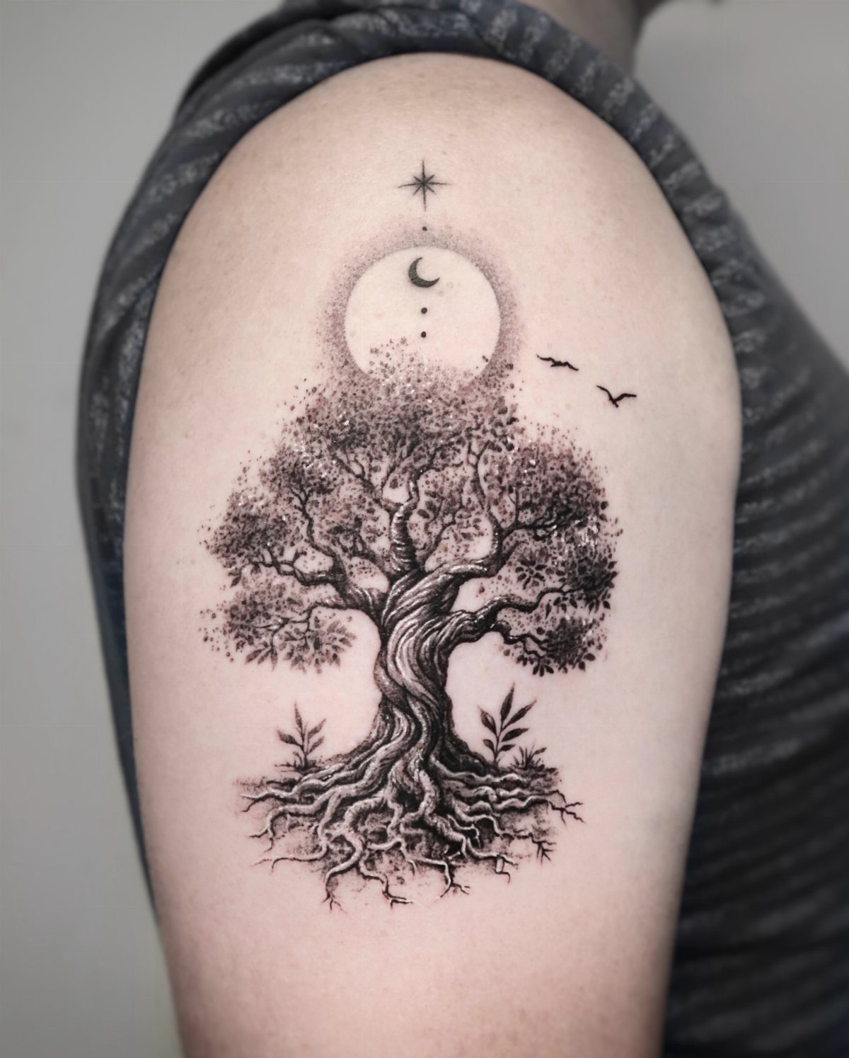 Tree of life tattoo on an upper arm with moon and star details.
