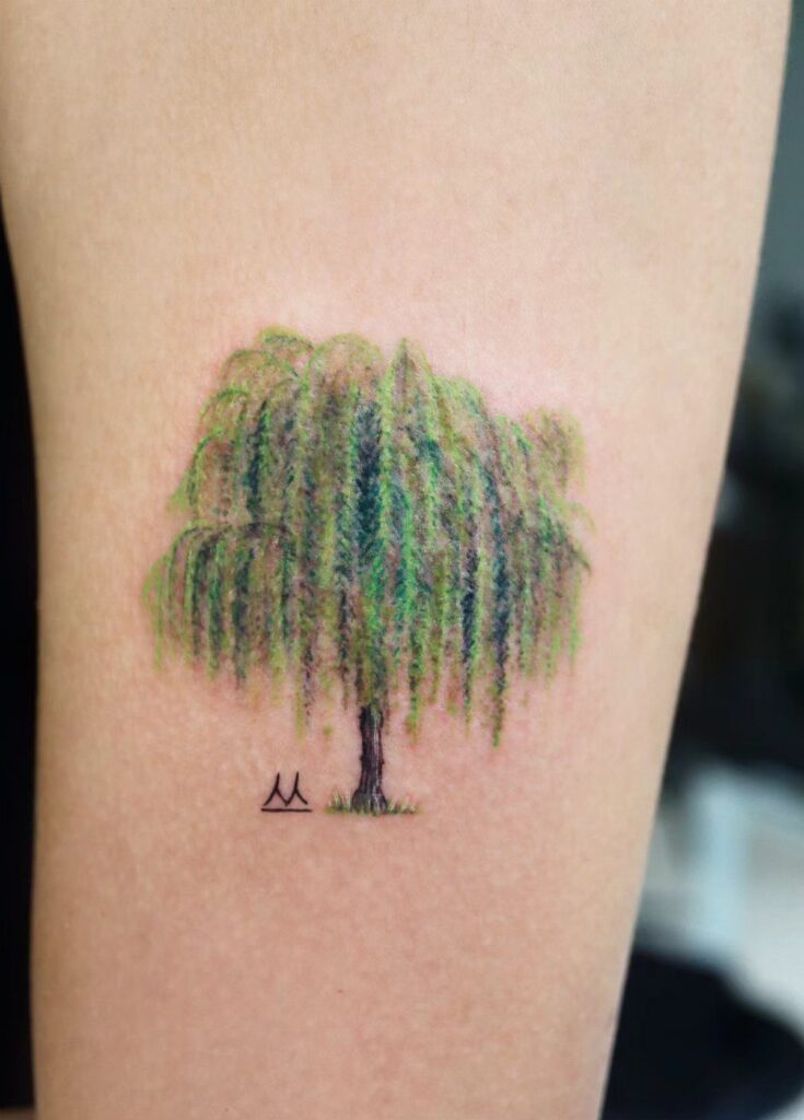 Willow tree tattoo with green leaves and small mountains on a person's arm